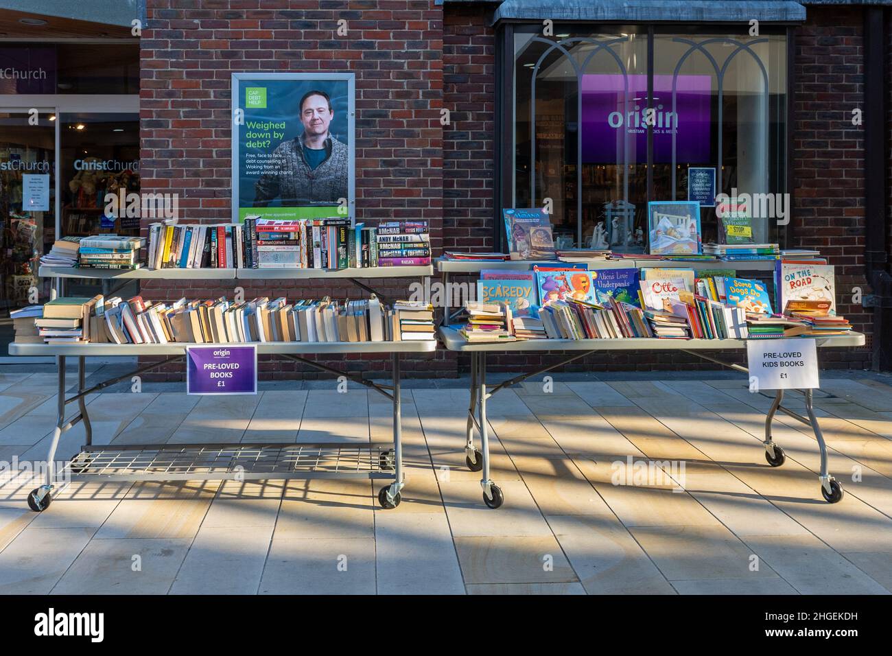 Libro stalla fuori di una chiesa con un poster che offre aiuto con il debito di consulenza, centro città di Woking, Surrey, Regno Unito Foto Stock