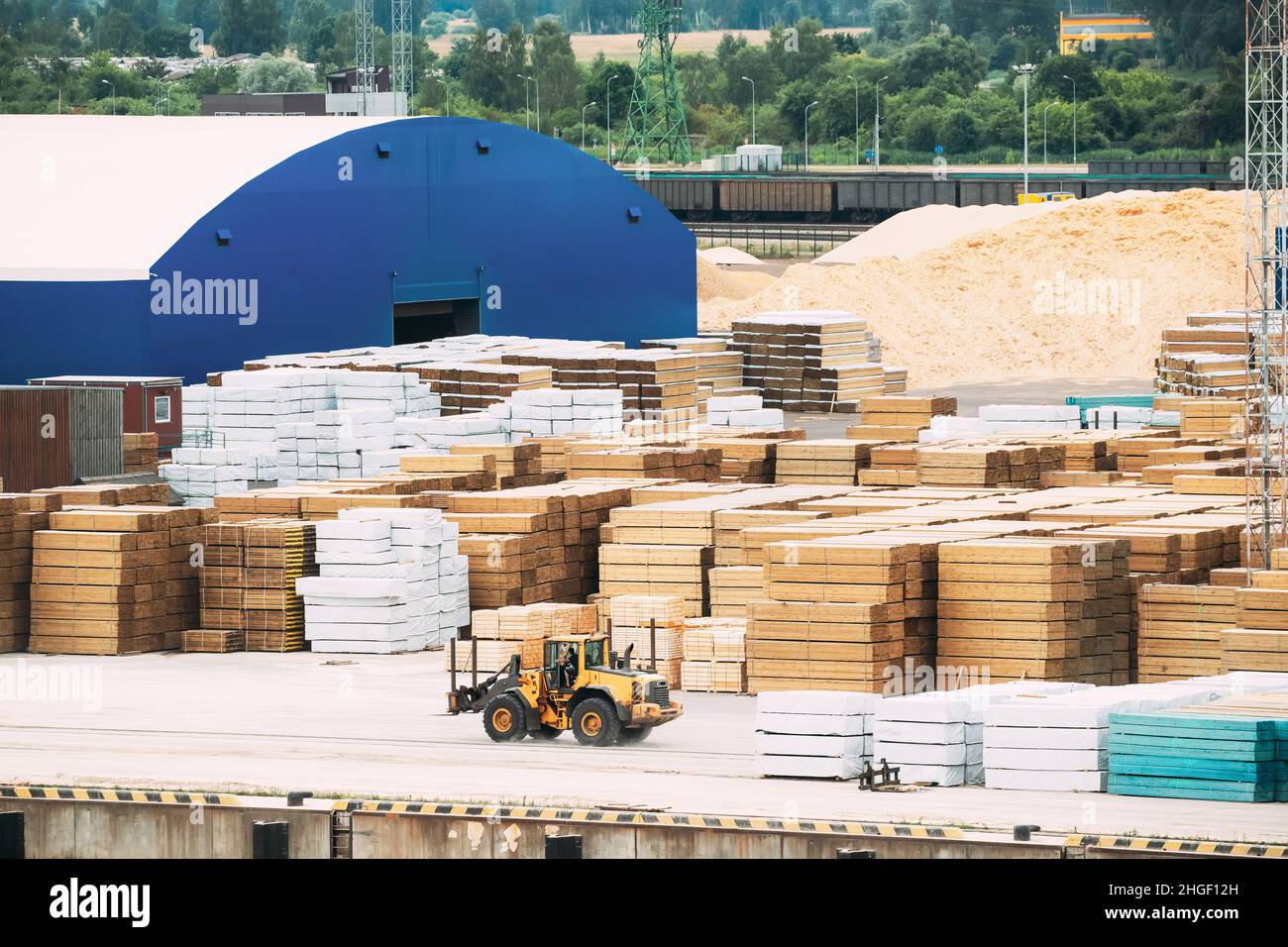 Industriale unità di carrello elevatore a forche vicino al legname accatastati in magazzino. Carrello elevatore, Jitney, carrello forche e forche di sollevamento e del carrello elevatore a forche lavorando nei pressi di legname industriale Foto Stock