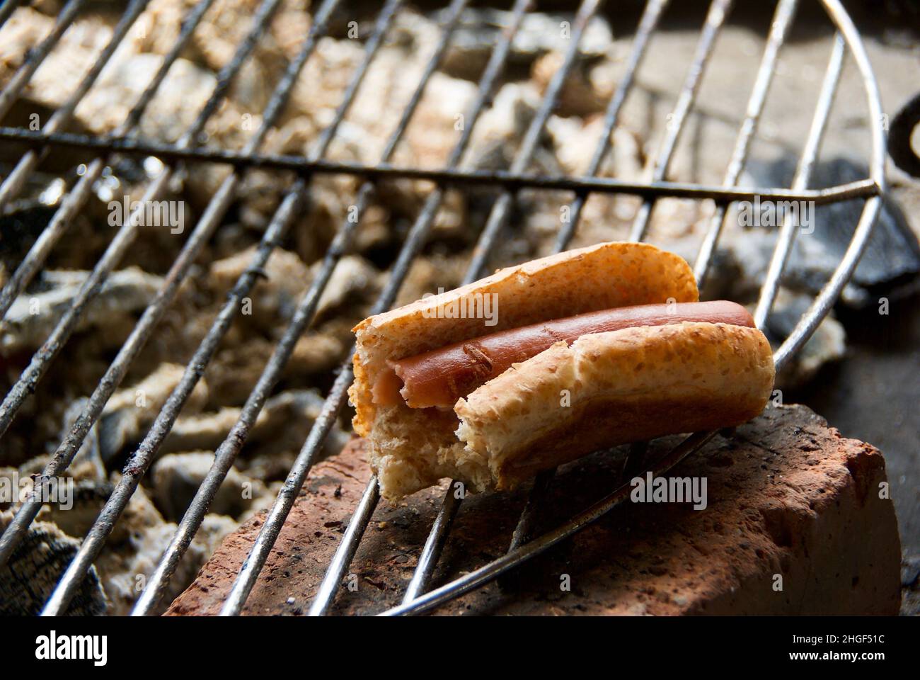 Salsiccia al barbecue con salsiccia pane all'aperto sul trellis alla griglia. Foto Stock