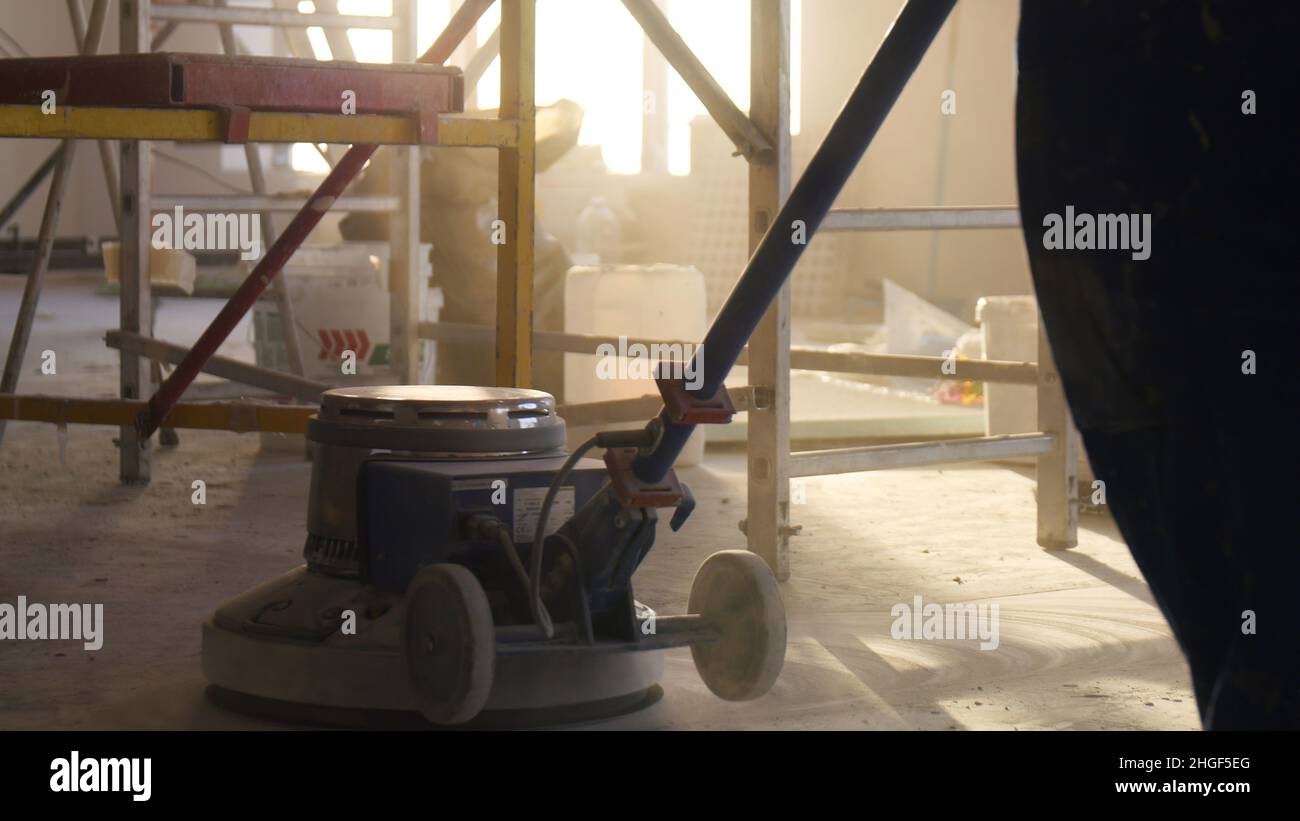 Lucidatrice per pavimenti. Lavori di ristrutturazione, levigatura parquet, lucidatura. L'uomo lucida i pavimenti in camera. Riparazione di appartamenti in un expe Foto Stock
