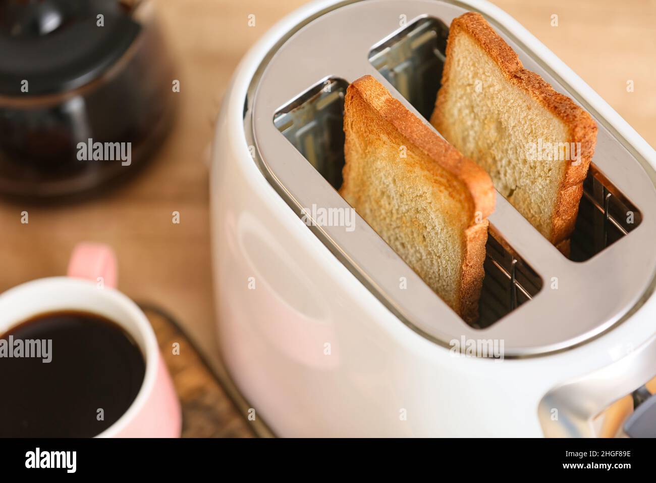 Tostapane bianco con fette di pane e una tazza di caffè sul tavolo, primo  piano Foto stock - Alamy