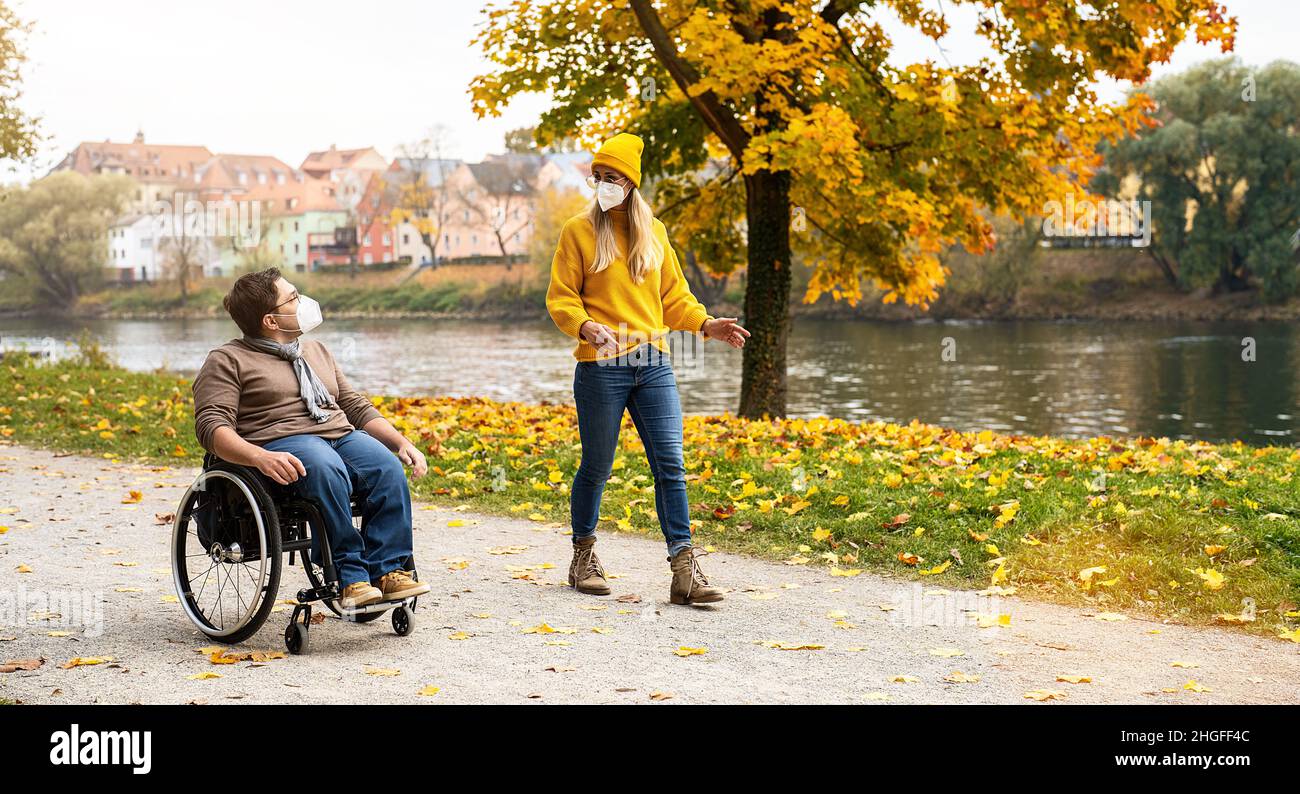 Donna e il suo ragazzo handicappato in sedia a rotelle, indossando FFP2 durante la pandemia di covid-19 Foto Stock
