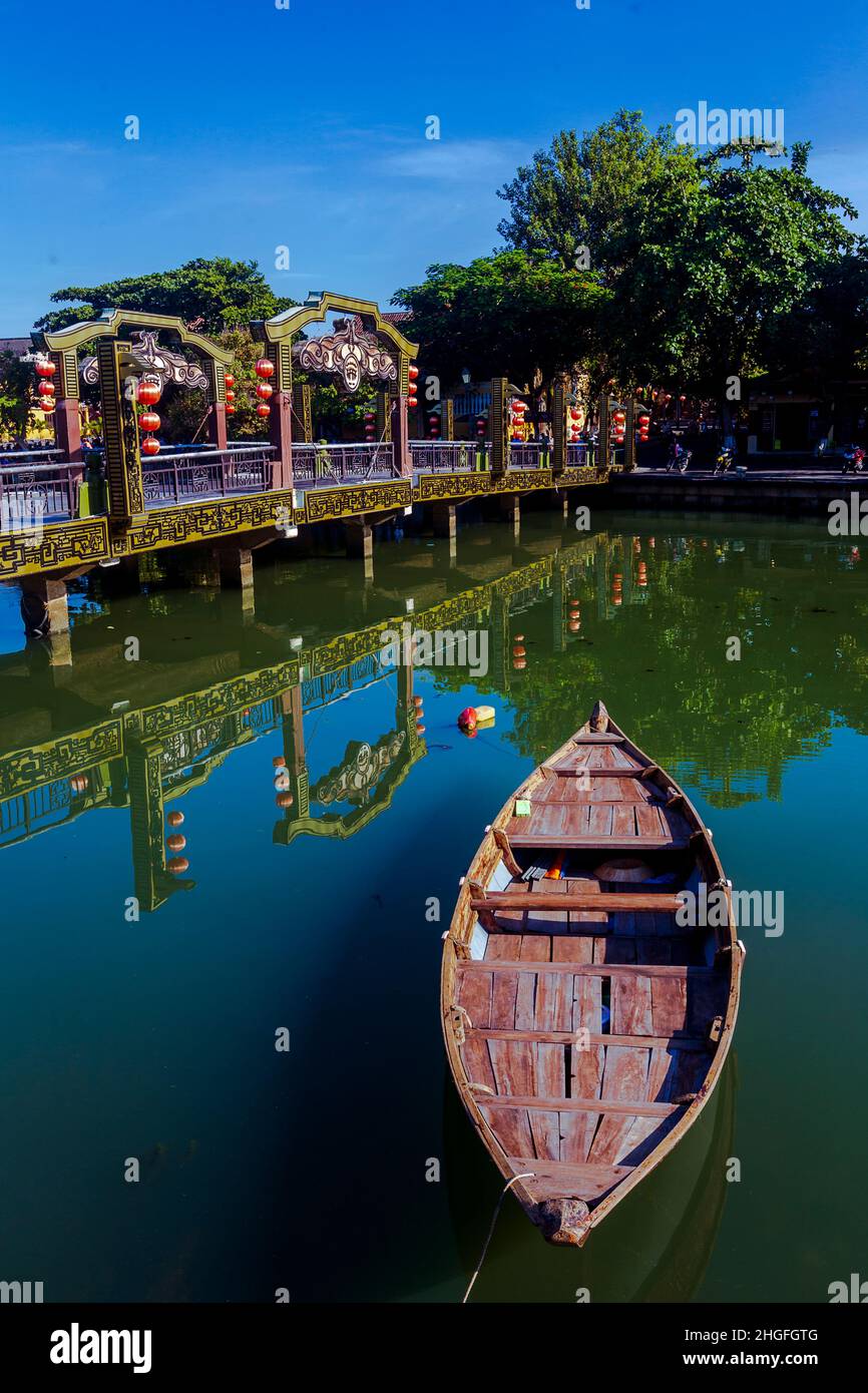Una piccola barca di legno in primo piano punta al popolare Ponte delle Lanterne nella Città Vecchia, Hoi An. Foto Stock