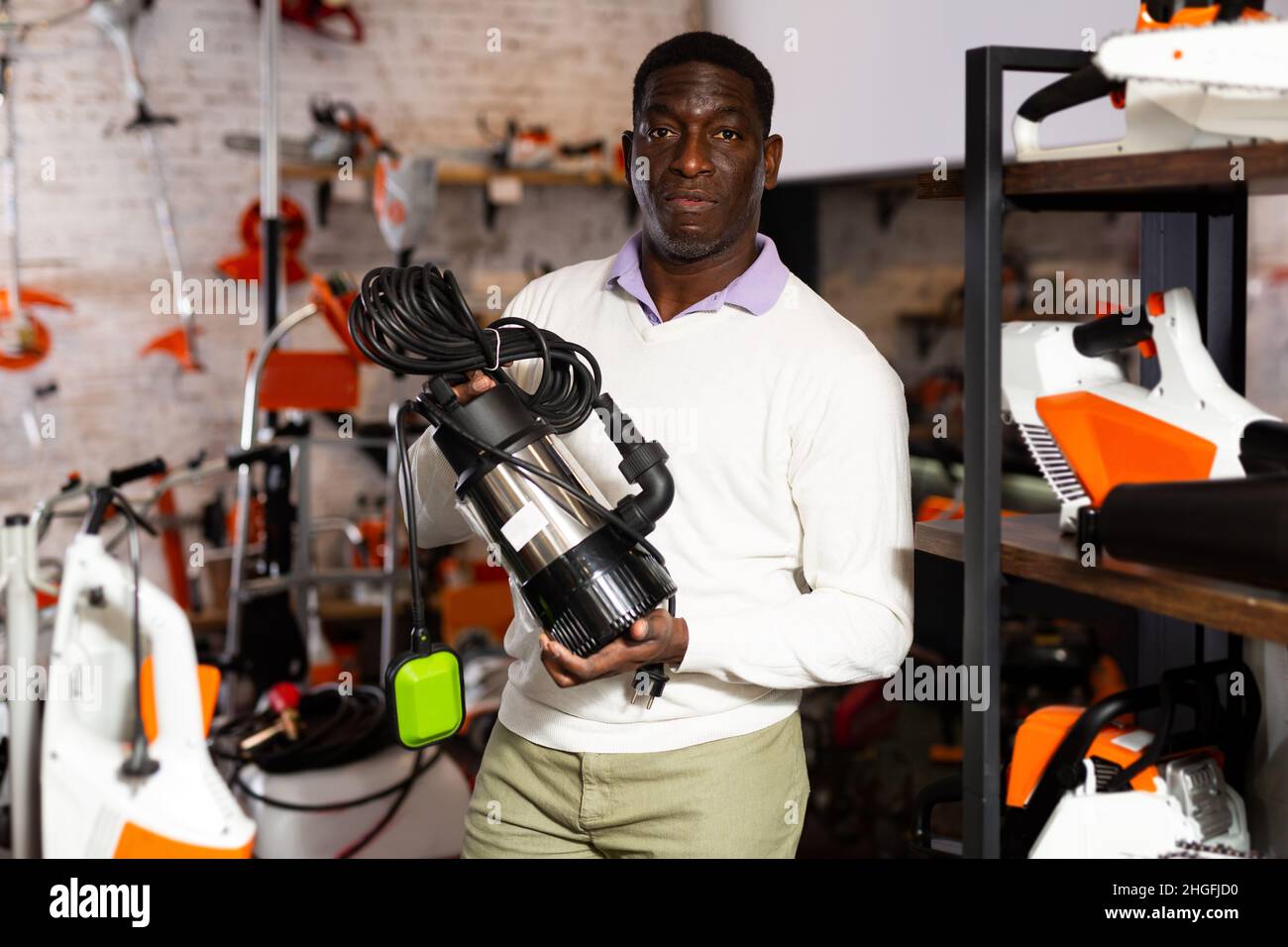 Uomo che decide sulla pompa sommergibile migliore nel negozio di attrezzatura da giardino Foto Stock