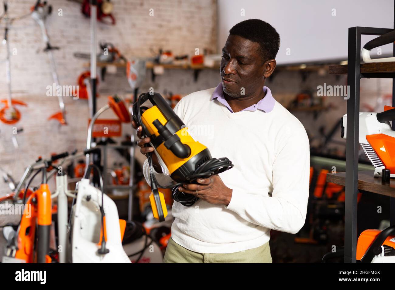 Uomo che decide sulla pompa sommergibile migliore nel negozio di attrezzatura da giardino Foto Stock