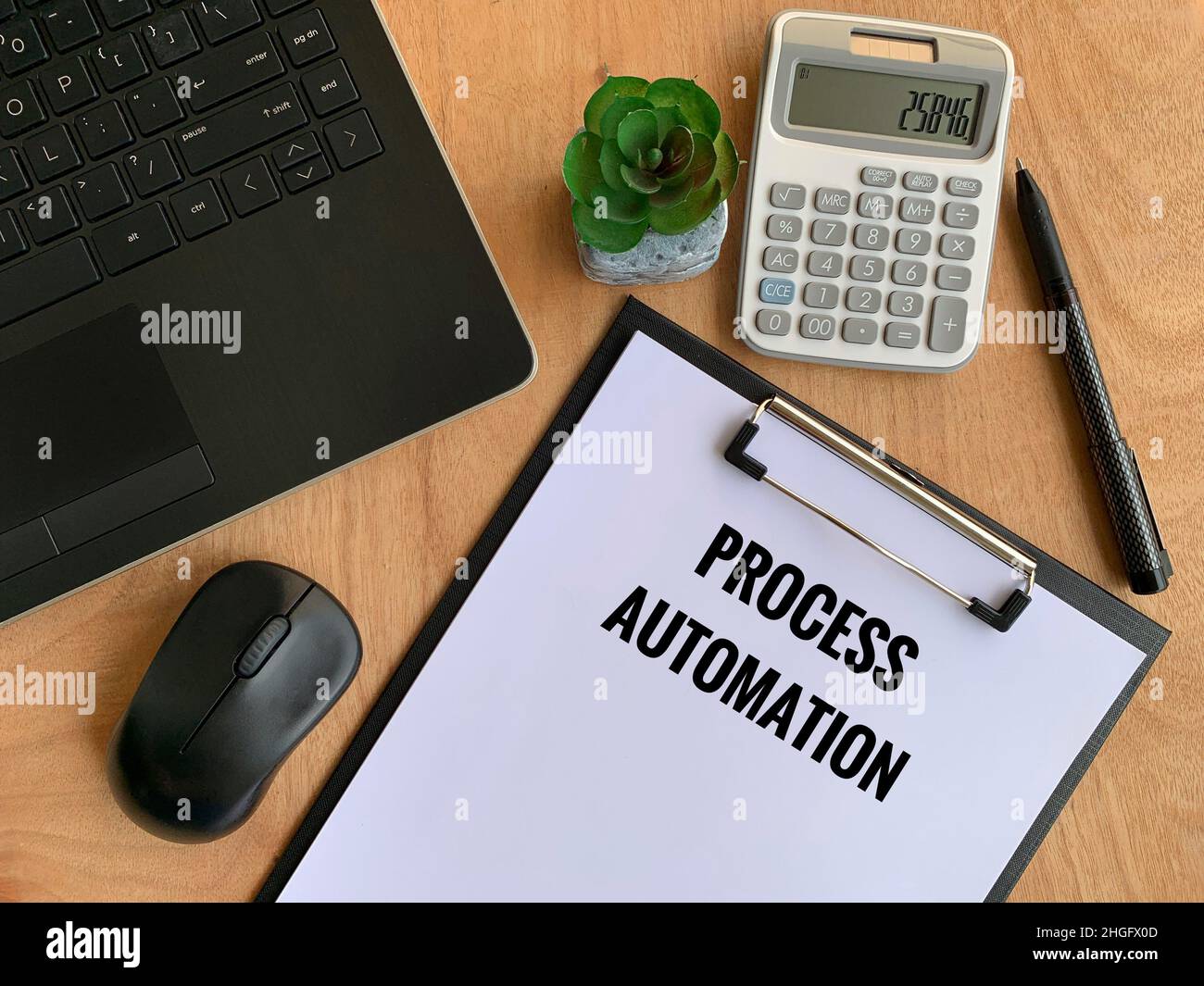 Testo di automazione dei processi scritto su carta con laptop, penna, calcolatrice, mouse e sfondo marrone della tabella. Concetto aziendale Foto Stock