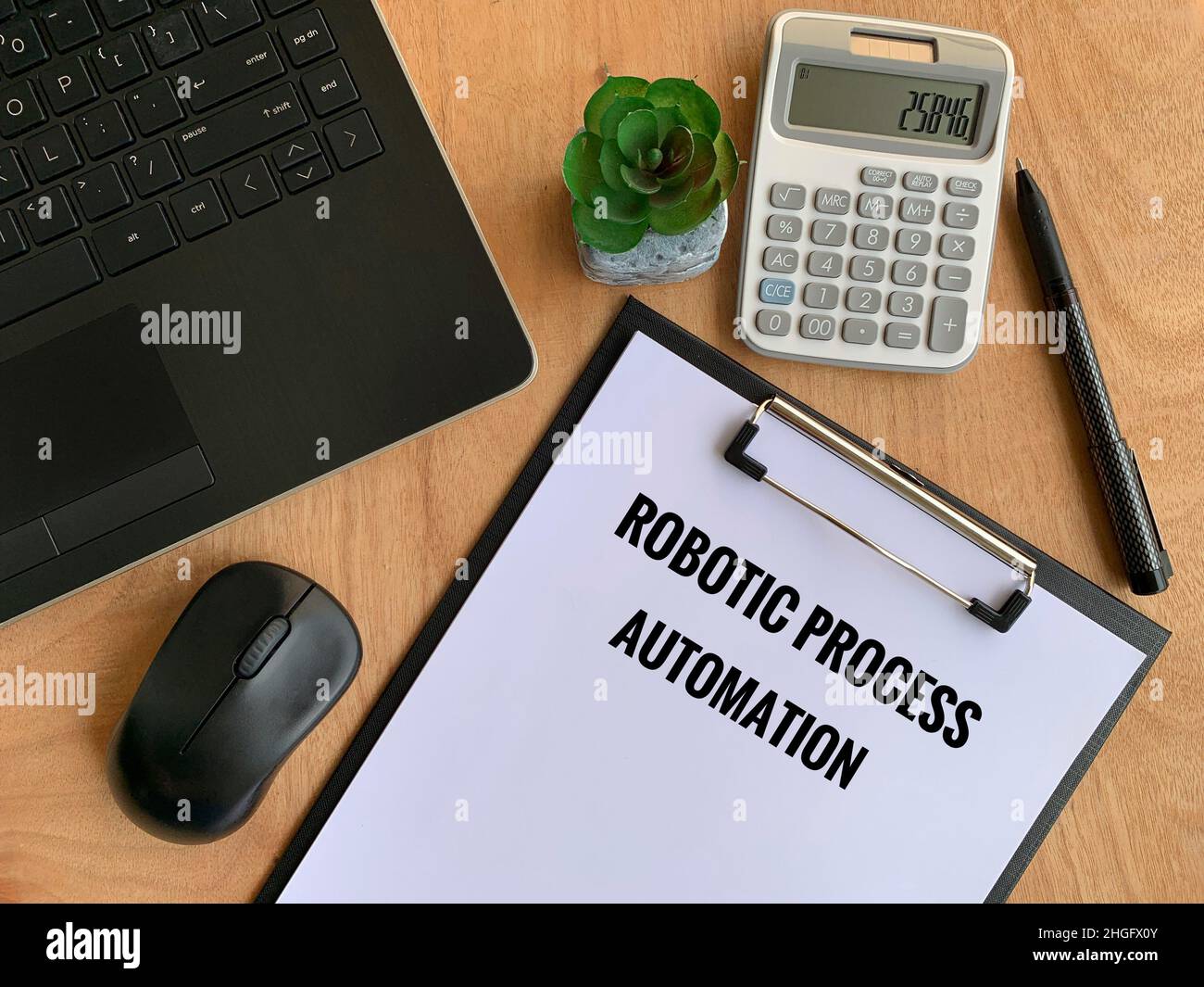 Automazione dei processi robotica testo su carta con laptop, penna, calcolatrice, mouse e sfondo marrone del tavolo. Concetto aziendale Foto Stock