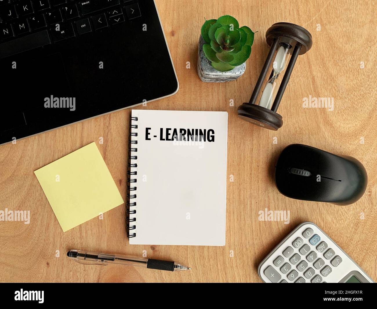 Testo di e-learning su notebook con notebook, penna, calcolatrice, mouse, sfondo in clessidra. Concetto di business online Foto Stock