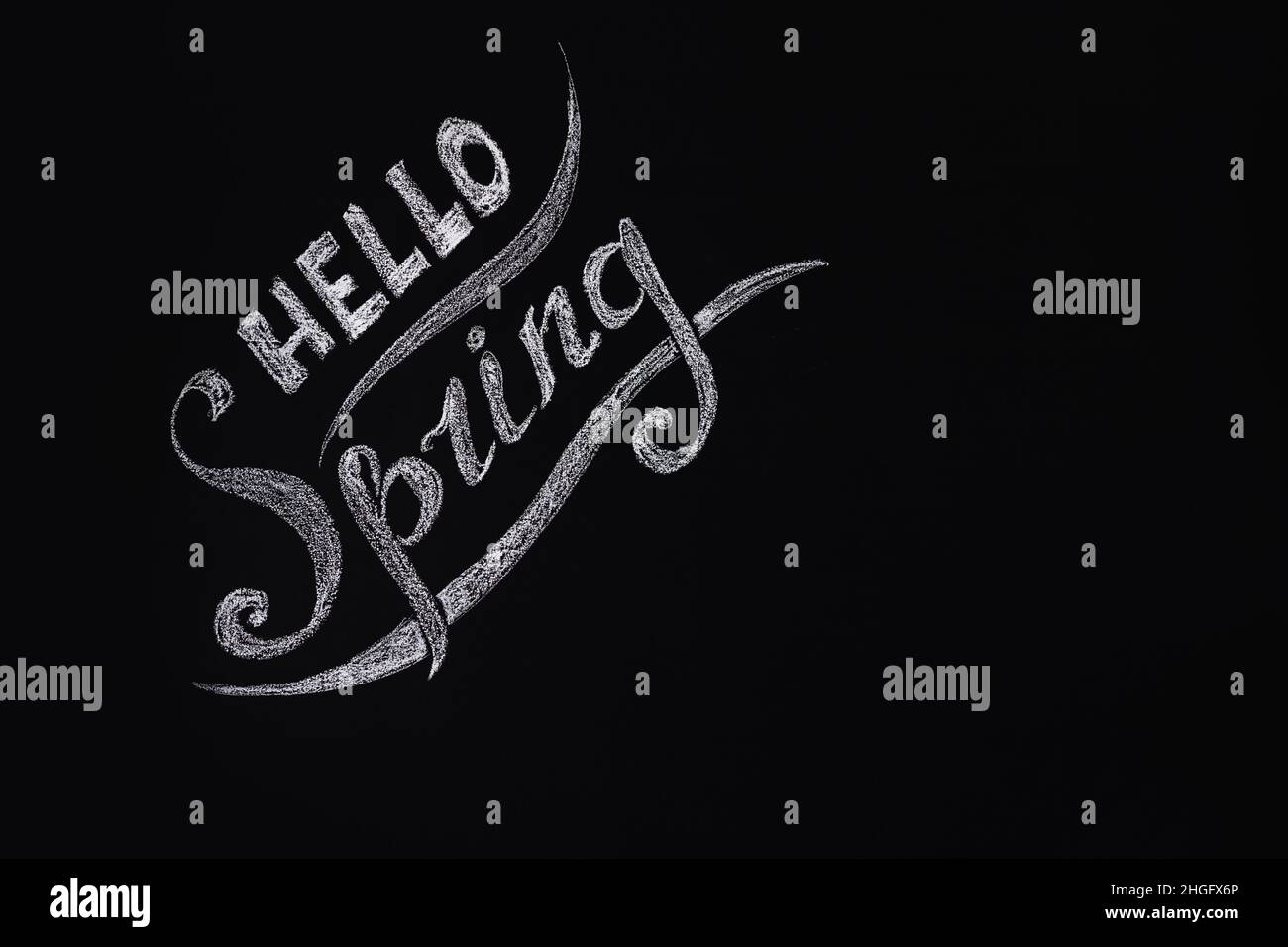 Ciao primavera. Foto stagionale, un'iscrizione su sfondo scuro di una parete o lavagna in ardesia. Vista frontale. Posiziona per testo. Foto Stock