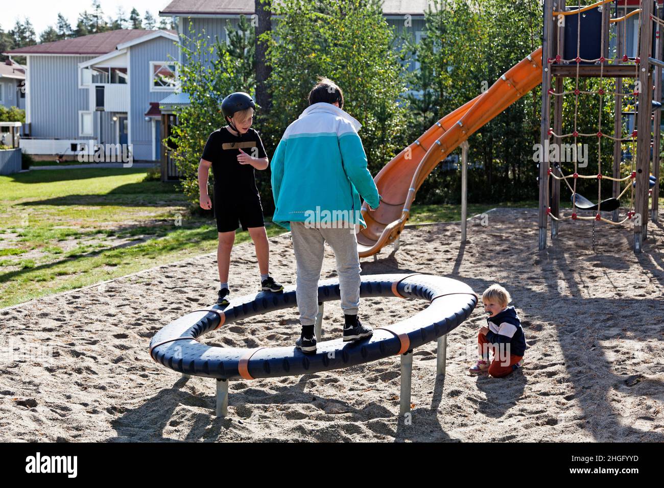 Umea, Norrland Svezia - 19 settembre 2020: Tre bambini giocano con una ruota grande in un sandbox Foto Stock