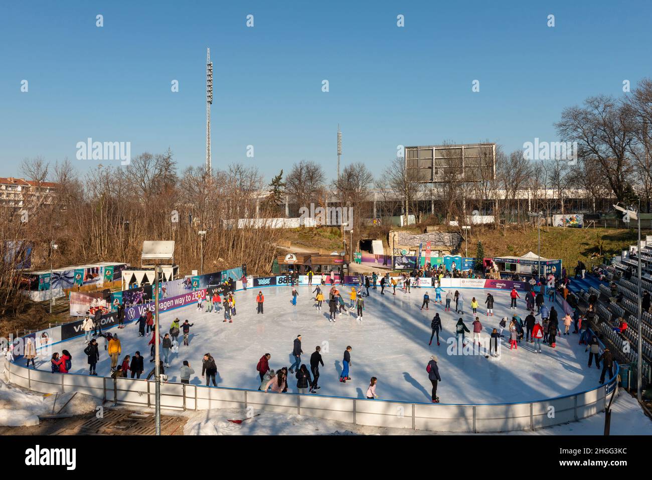 La gente si diverte nella pista di pattinaggio all'aperto dello stadio Yunak nella soleggiata giornata invernale di Sofia, Bulgaria Foto Stock