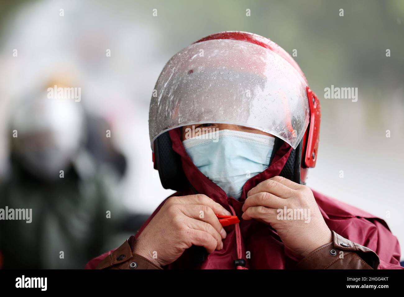 LIUZHOU, CINA - 20 GENNAIO 2022 - i lavoratori migranti guidano una motocicletta per tornare a casa sotto la pioggia sulla National Highway 209 a Liuzhou City, Guangxi Zhu Foto Stock