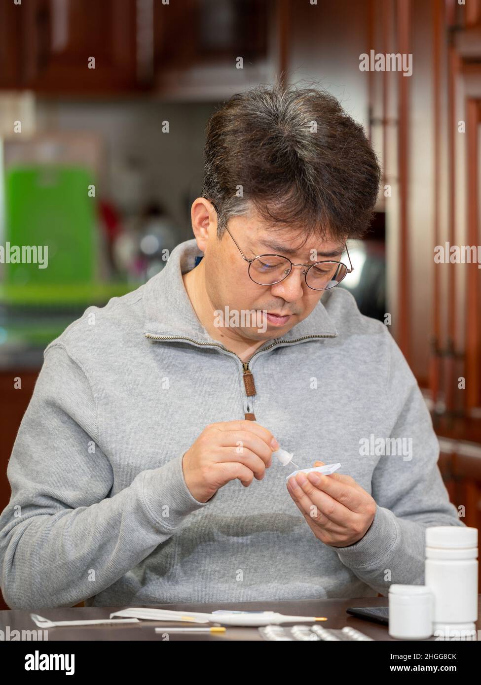 Uomo asiatico di mezza età che fa test di antigene rapido per COVID-19 a casa. Foto Stock
