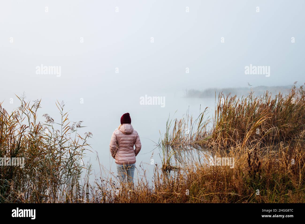 Donna in piedi accanto al lago. Divertimento e sensazione di armonia con la natura. Misty mattina alle basse temperature Foto Stock