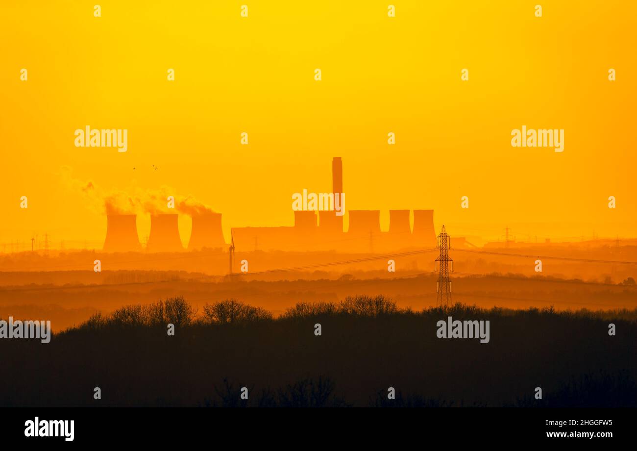 Vista lontana dai Yorkshire Wolds delle torri di raffreddamento di una centrale elettrica vicino a Drax nel North Yorkshire. Il sole tramonta su una fredda notte invernale Foto Stock