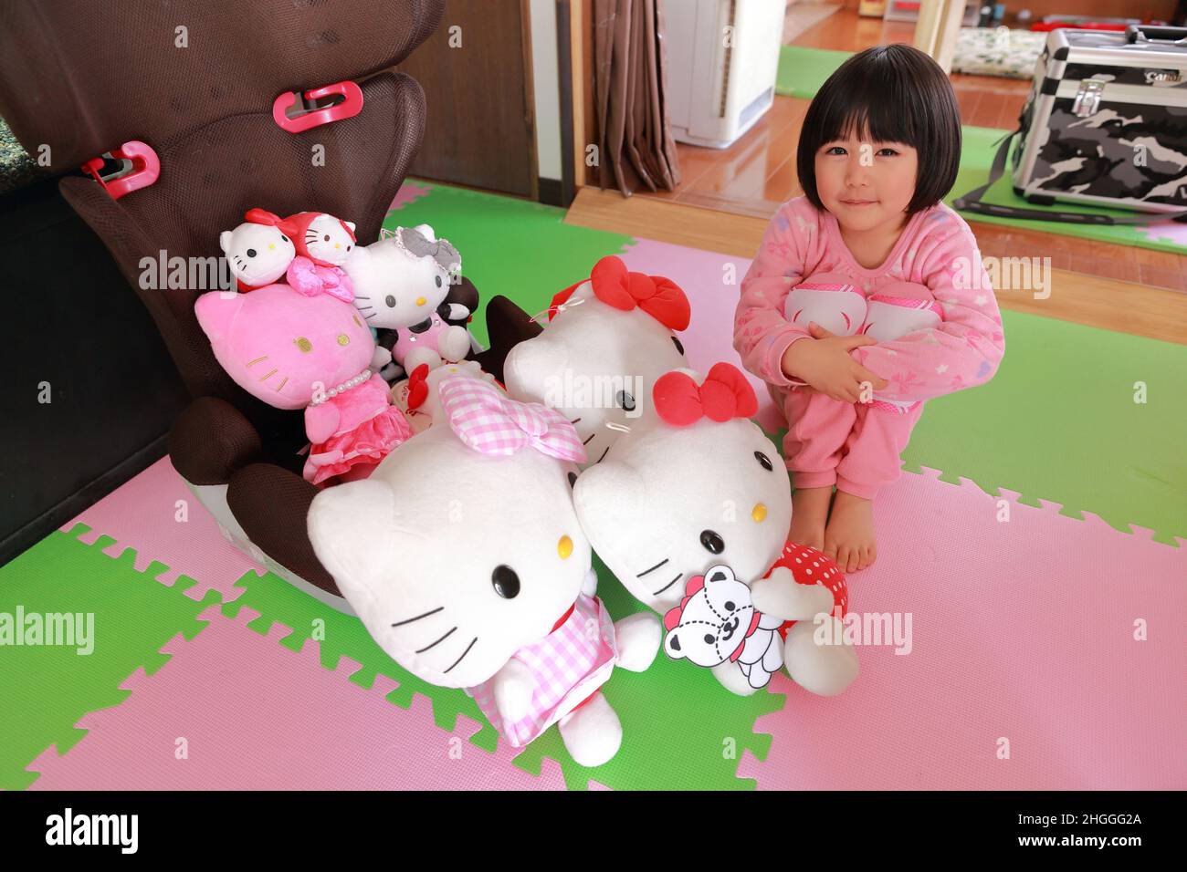 Bambino a casa con il suo carino preferito Ciao Kitty ripieni Toys Foto Stock