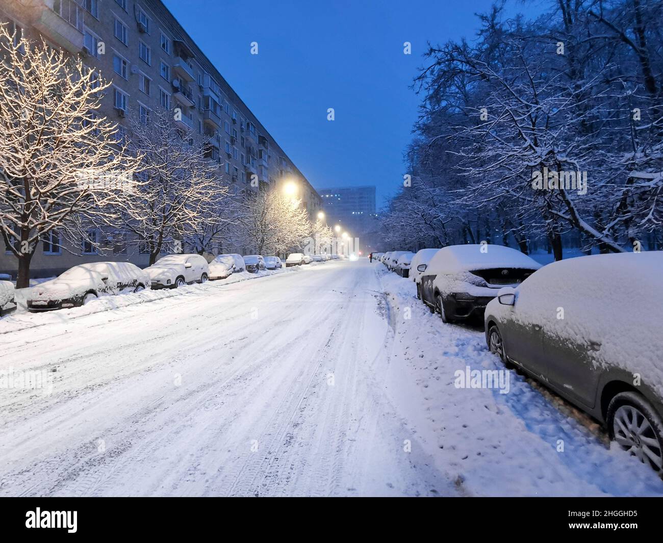 Le auto coperte di neve sono parcheggiate su una strada coperta di neve a Mosca in enormi nevicate. Mattina presto in città dopo nevicate e bizzard. Foto Stock