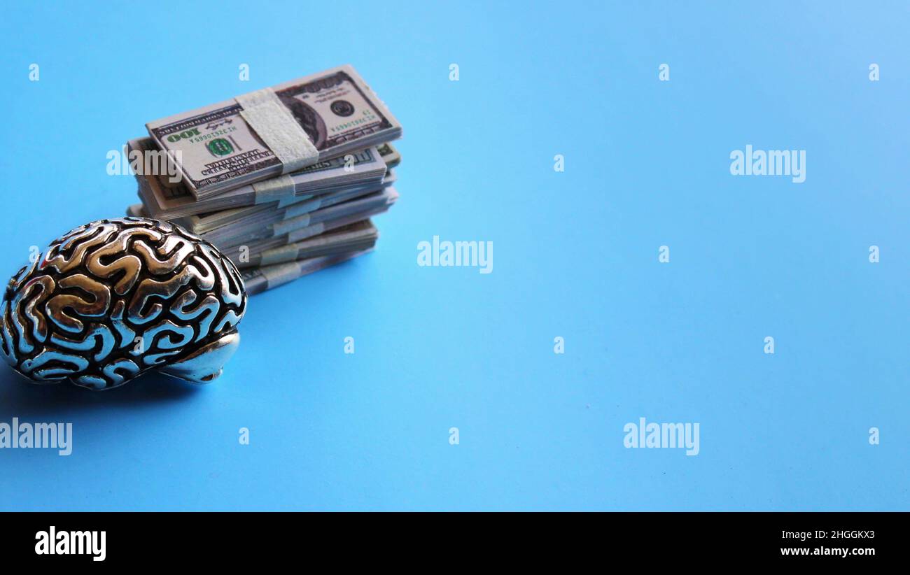 Concetto orientato al business. Modello del cervello e pila di soldi su sfondo blu con spazio di copia Foto Stock