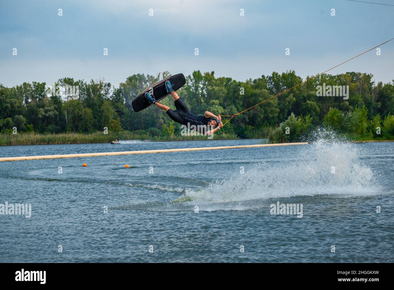 Il pilota esperto del wakeboard salta e gira in aria tenendo il cavo di traino Foto Stock