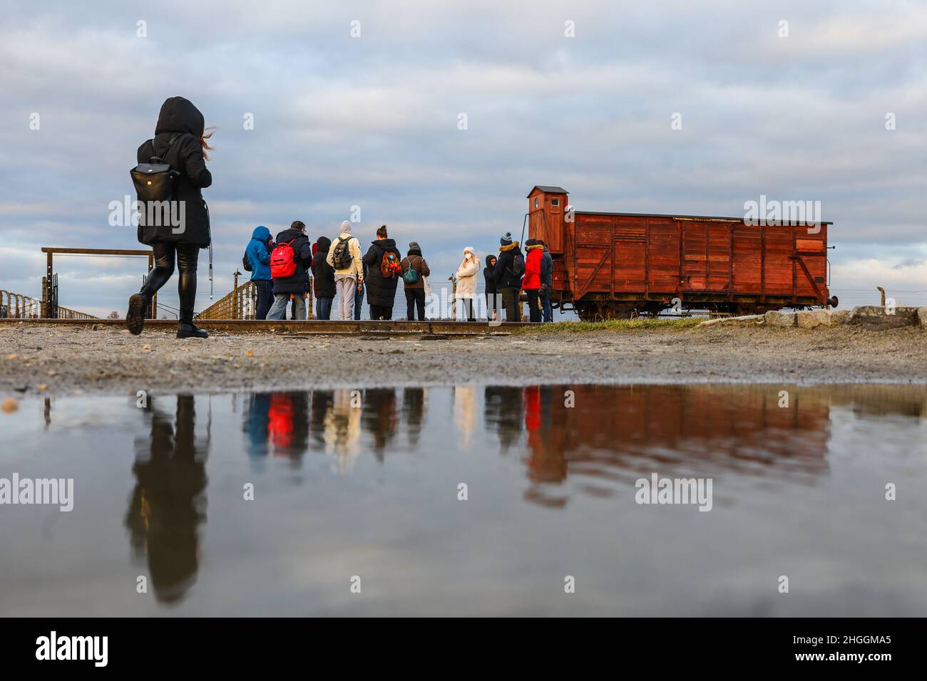 I visitatori si trovano accanto a un'originale carrozza ferroviaria utilizzata per le deportazioni presso l'ex campo di concentramento e sterminio nazista di Auschwitz II-Birkenau a Oswiecim, in Polonia, il 2 gennaio 2022. Foto Stock