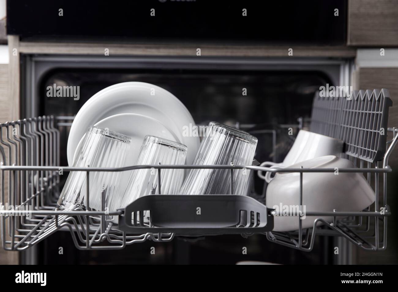 Vista frontale della lavastoviglie automatica aperta completamente integrata con utensili puliti, posate, all'interno della moderna cucina casalinga. Casa, elettrodomestici da cucina, vista sullo stile di vita Foto Stock