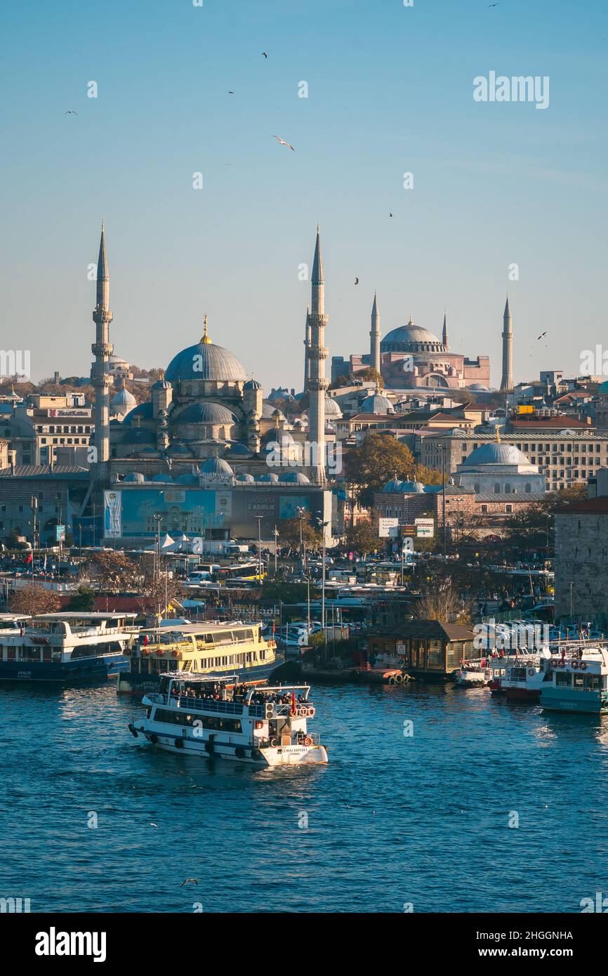 Istanbul Corno d'Oro, vista sul molo Eminönü con barche e moschea di Rüstem Pacha e moschea di Hagia Sophia sullo sfondo sotto un cielo blu Foto Stock