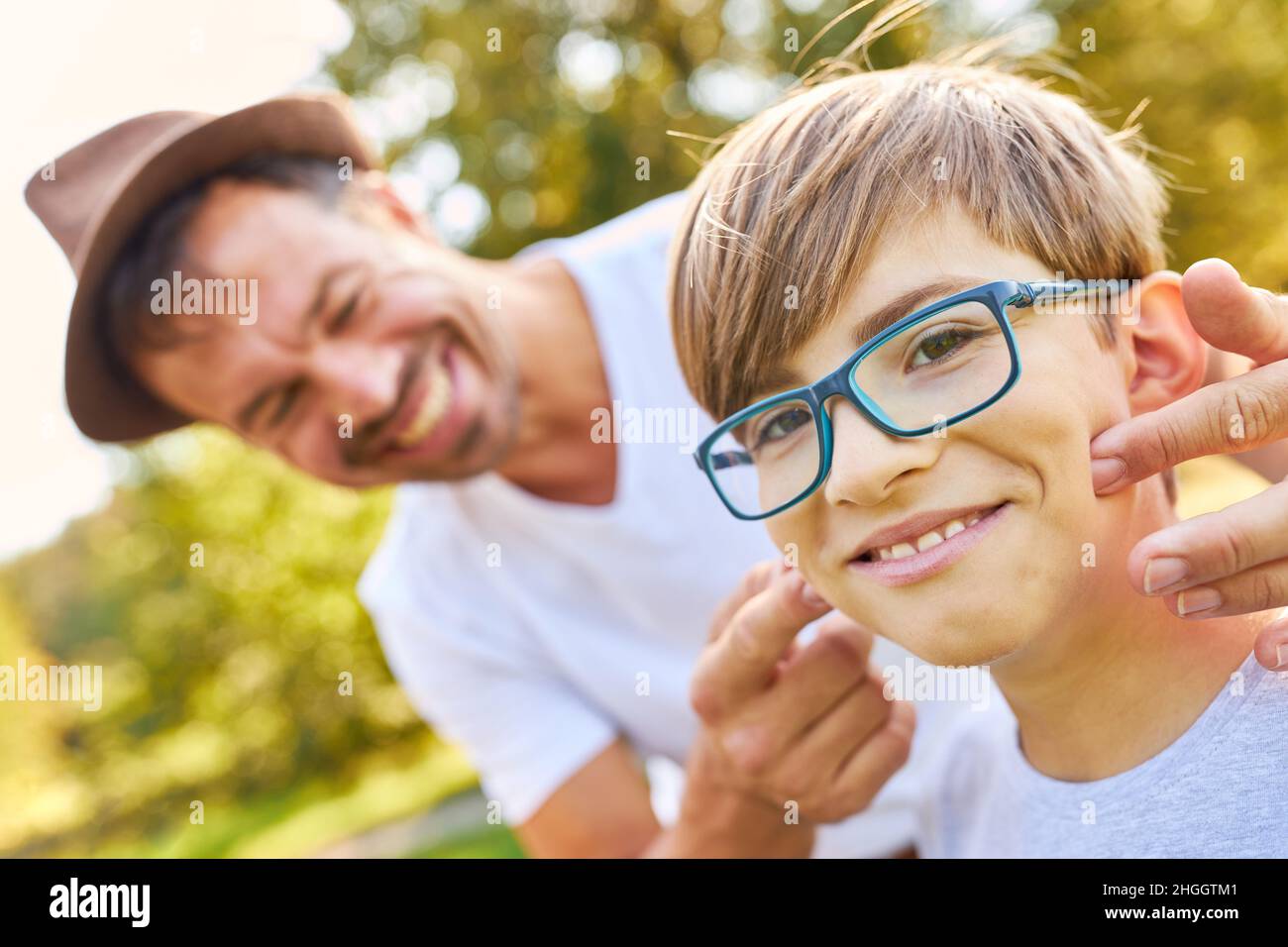 Padre insegna a suo figlio gli occhiali durante una vacanza estiva nel parco Foto Stock