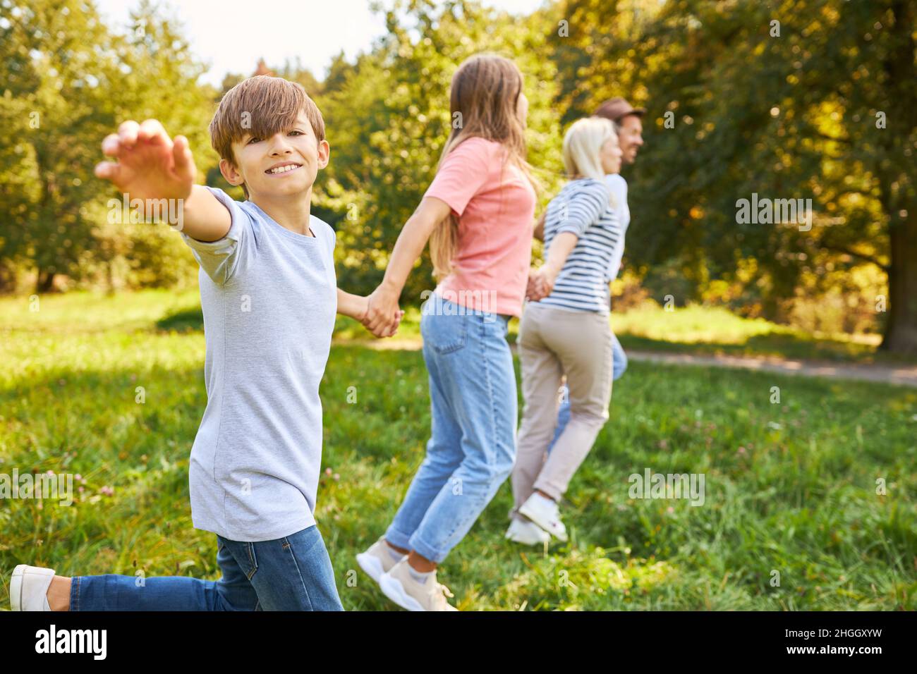 Ragazzo e famiglia in escursione in movimento su un prato in estate nella natura Foto Stock