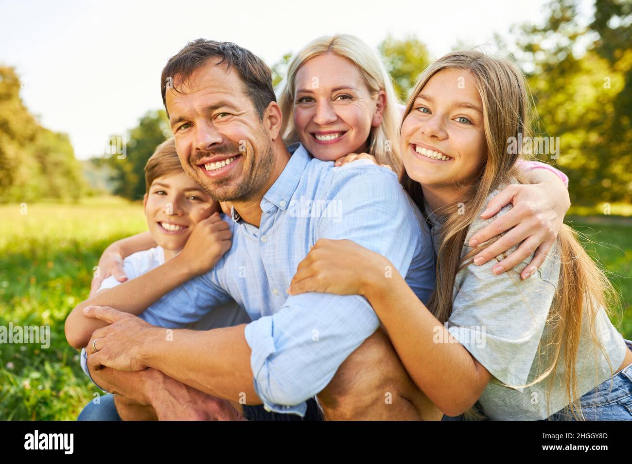 Famiglia felice con figlia e figlio siede in un abbraccio armonioso su un prato Foto Stock