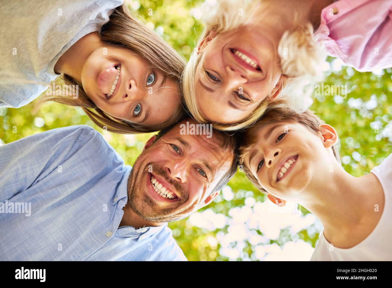 I genitori felici e due bambini felici si levano in piedi testa a testa e si ingannano intorno Foto Stock