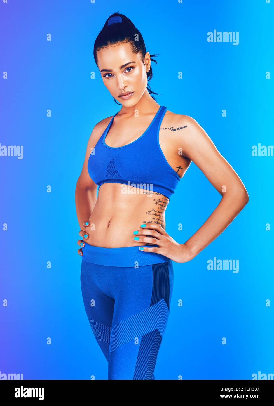 Scavate in profondità e mettete in forma. Ritratto da studio di un giovane sportivo attraente che posa con le mani sui fianchi su sfondo blu. Foto Stock