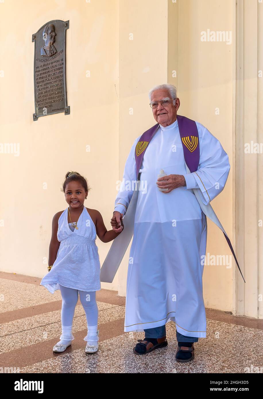 Sacerdote cattolico con una bambina all'ingresso della chiesa della basilica di nostra Signora della Carità di El Cobre a Santiago de Cuba, Cuba Foto Stock