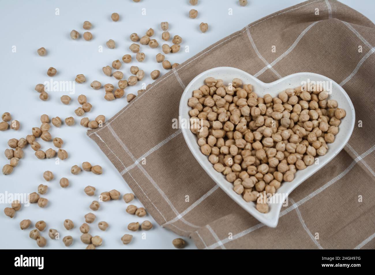 Ceci crudi sul piatto a forma di cuore e asciugamano. Vista dall'alto. Foto Stock