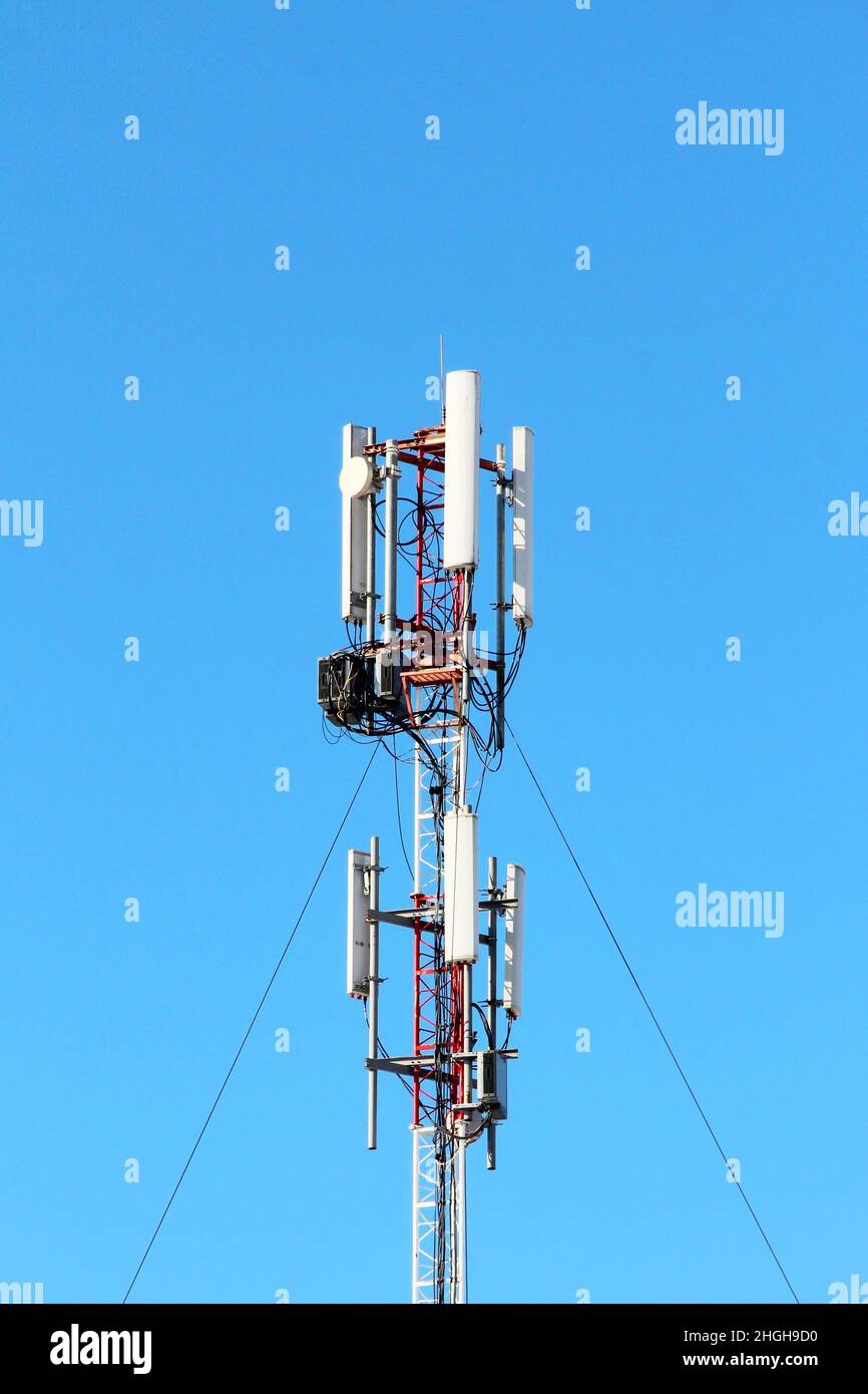 Antenna di rete mobile della stazione base su un montante con struttura in acciaio e un ripetitore. 3g, 4g, 5g. Sfondo blu cielo. Foto Stock