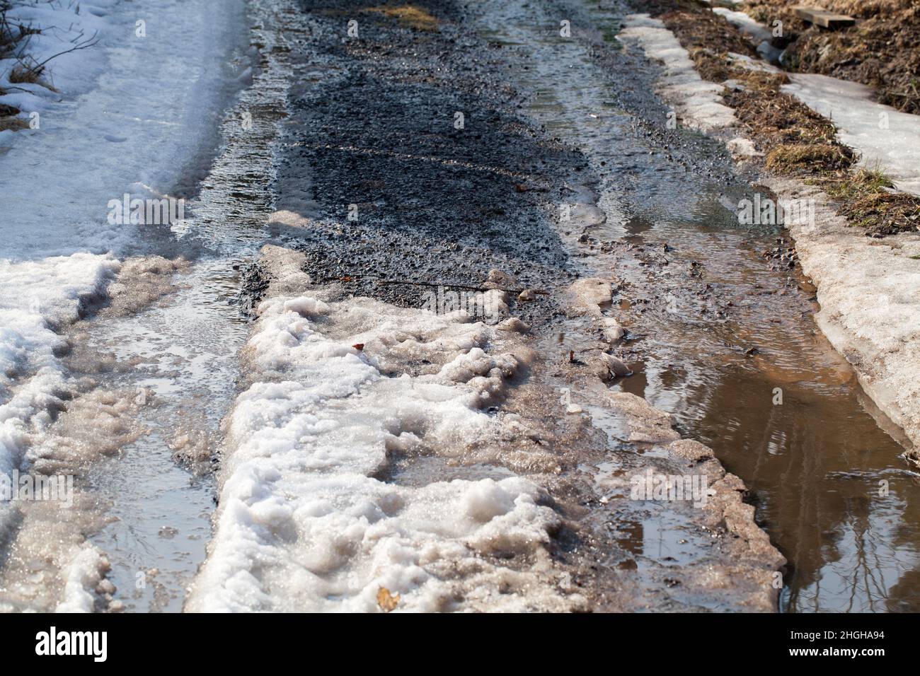 Strada sporca bagnata con neve e pozzanghere, foto di sfondo del trasporto Foto Stock