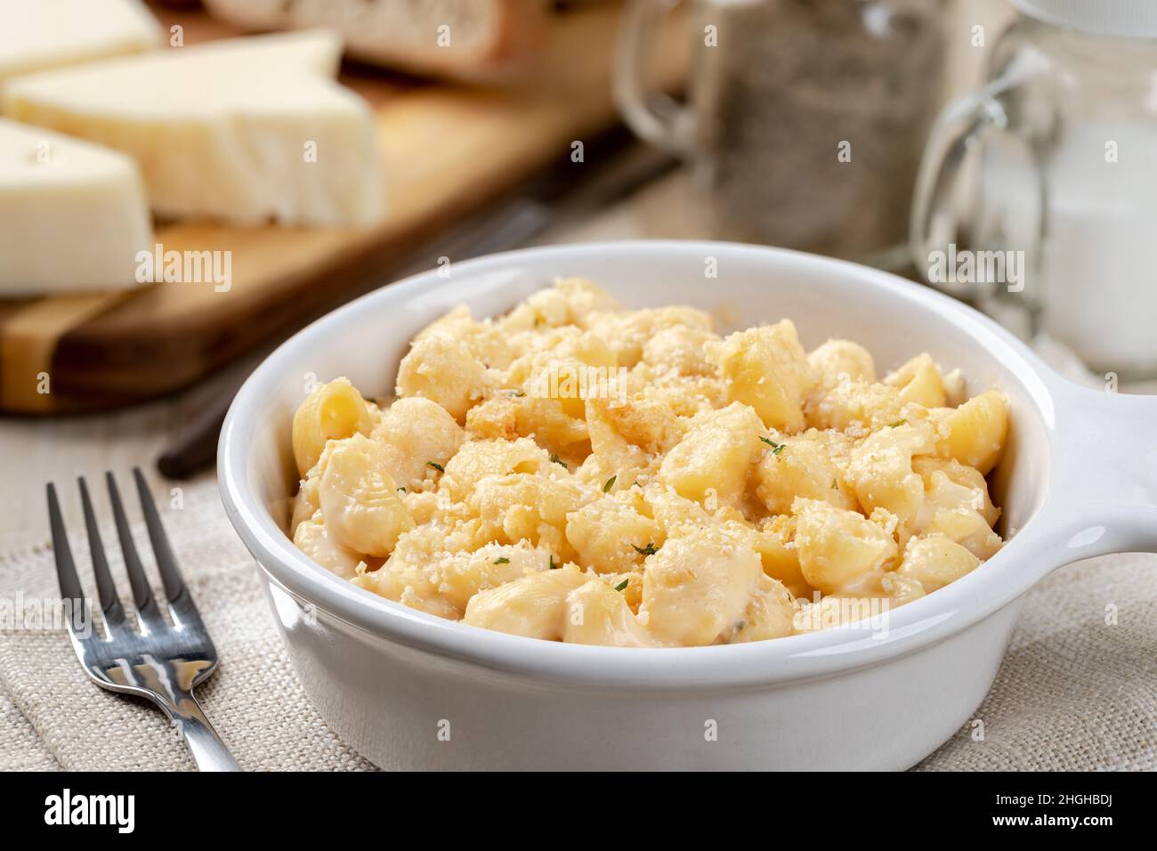 Primo piano di macaroni e formaggio cosparsi di parmigiano in una teglia bianca su un rustico tavolo di legno Foto Stock