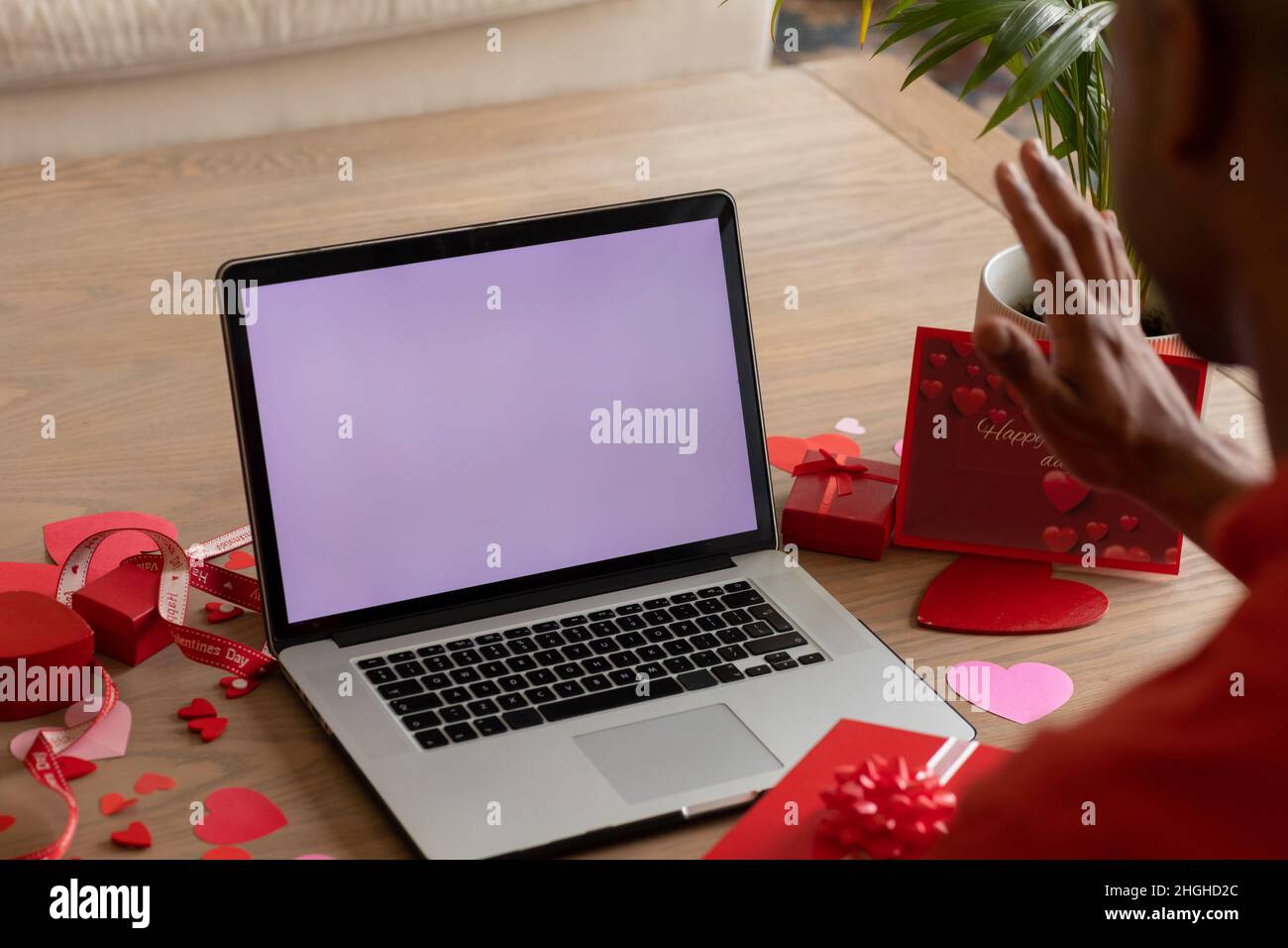 L'uomo afroamericano che ondeggia al laptop durante la videochiamata di San Valentino con lo schermo vuoto che mostra lo spazio per le copie Foto Stock