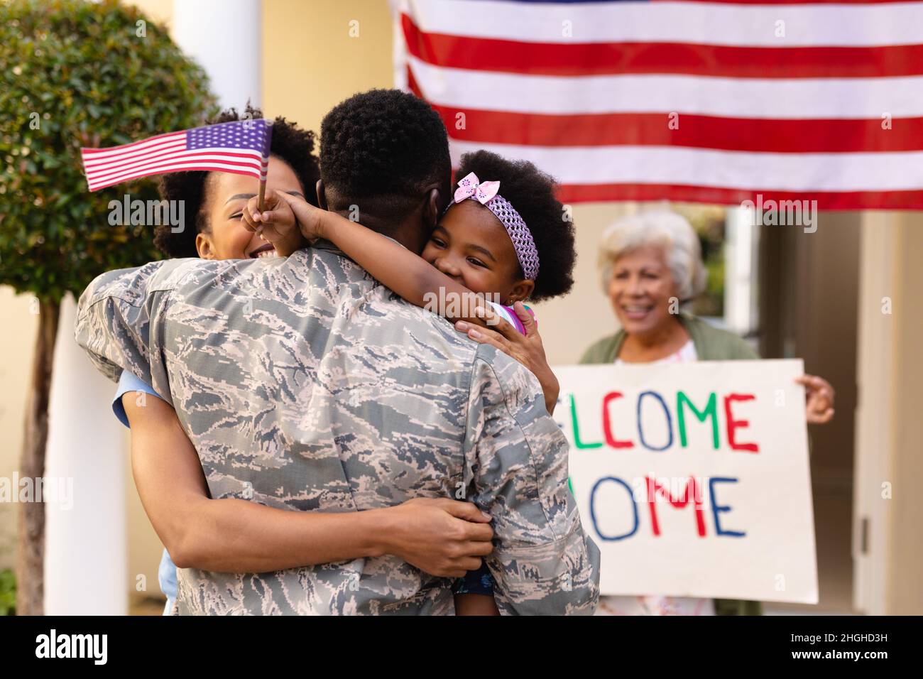 Soldato militare afroamericano che abbraccia donna e figlia all'ingresso Foto Stock