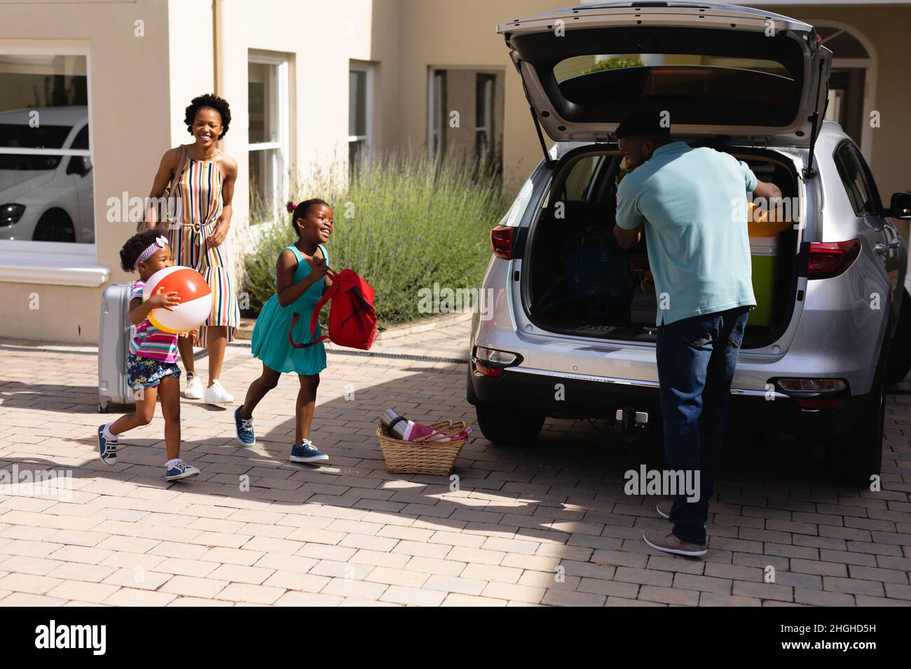Il padre afro-americano mette tutti i bagagli sul retro dell'auto Foto Stock