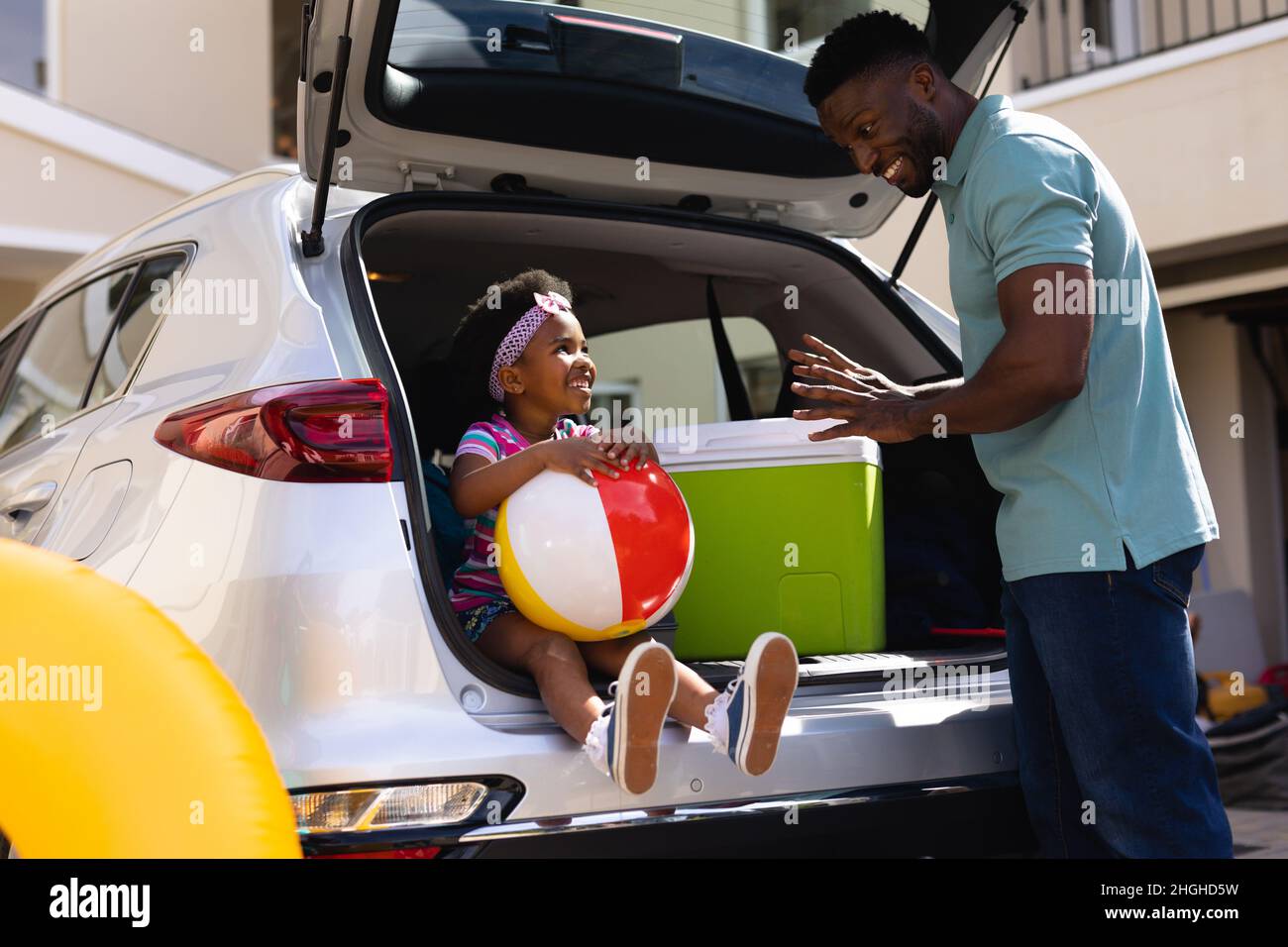 Il padre afroamericano parla con la figlia seduta nella parte posteriore dell'automobile Foto Stock