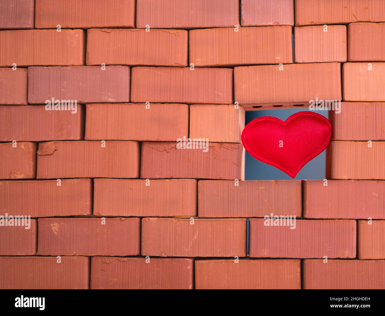 Costruzione di cuore liscio nel muro da mattoni ruvidi e testurizzati Foto Stock