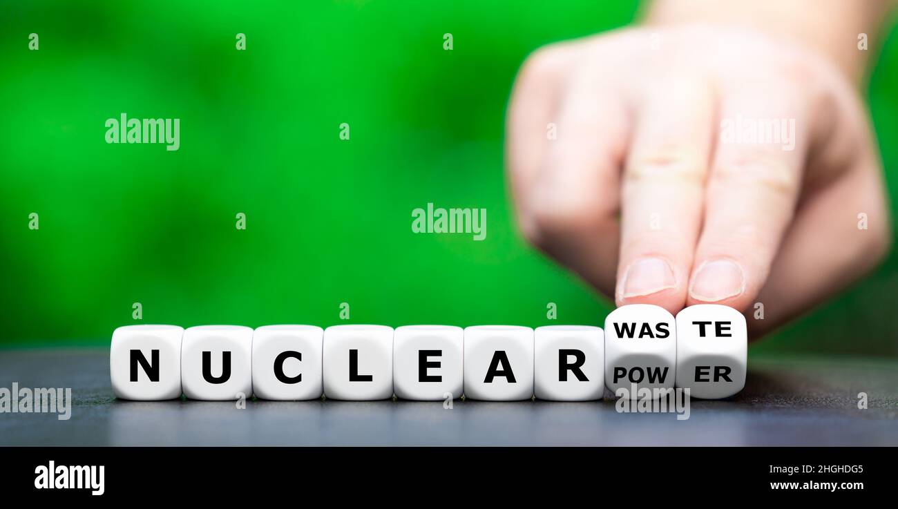 Simbolo contro l'energia nucleare. La mano gira i dadi e cambia l'espressione "energia nucleare” in "scorie nucleari”. Foto Stock