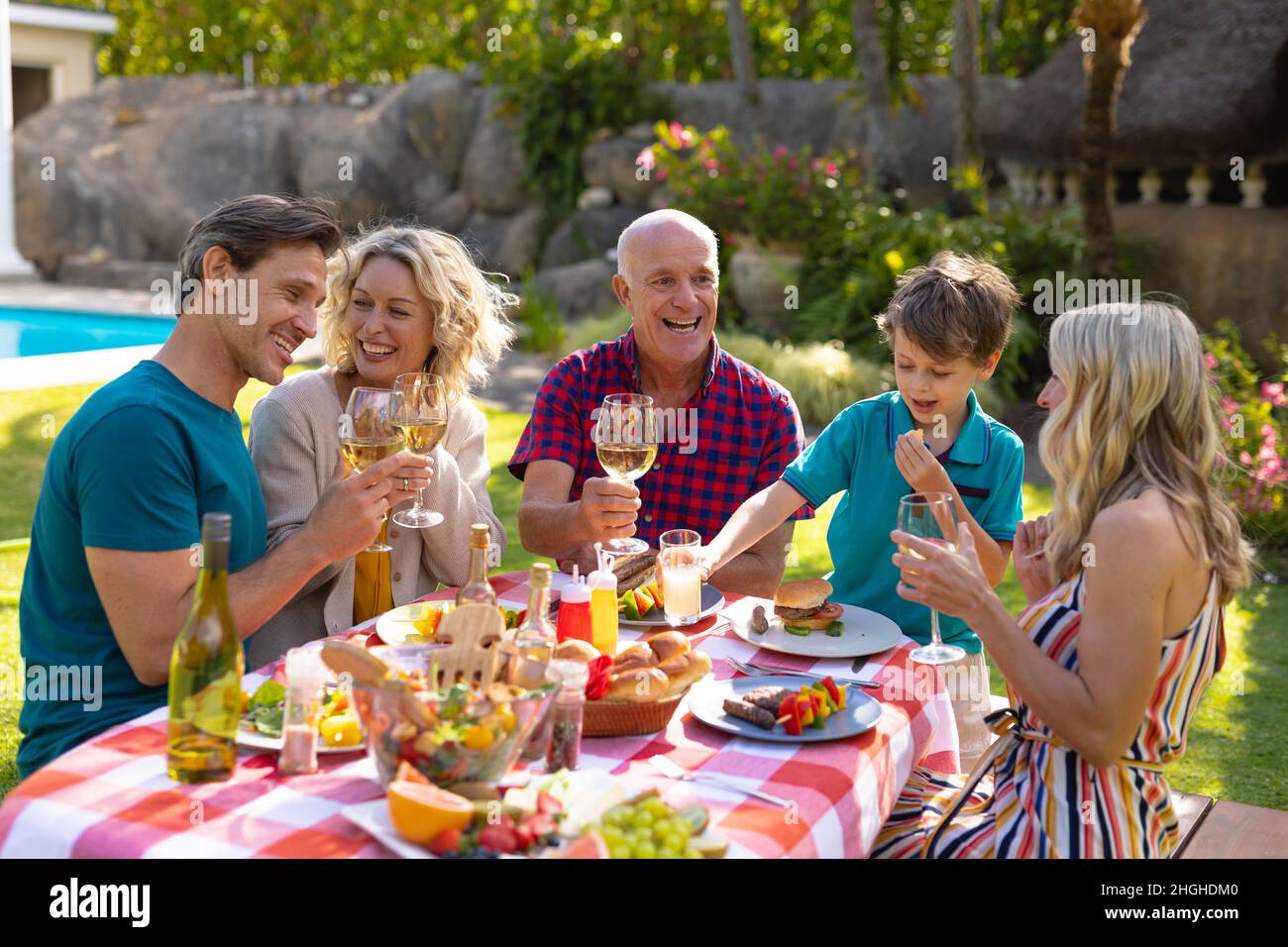 Famiglia caucasica di tre generazioni con pranzo a tavola in giardino Foto Stock