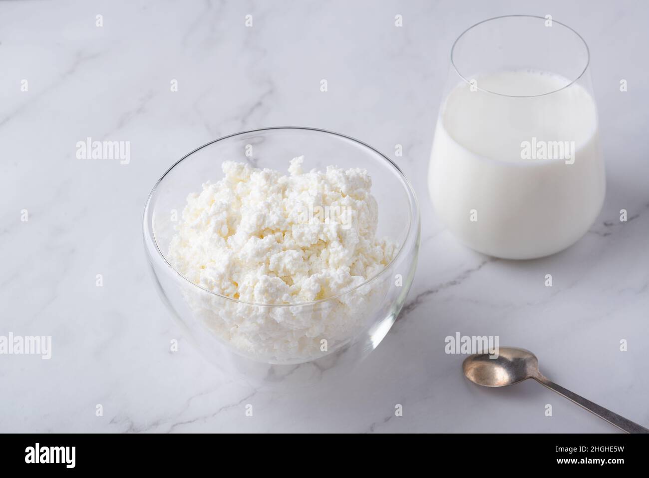 Ciotola con formaggio fresco e un bicchiere di latte sul tavolo. Spazio per il testo Foto Stock