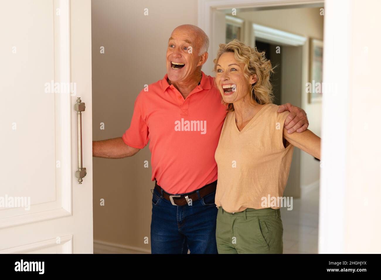 Sorprende la coppia di anziani caucasici sorridendo mentre si apre la porta d'ingresso della casa Foto Stock