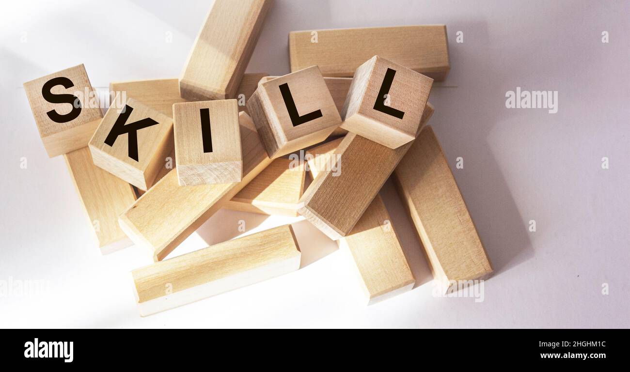 Un cubo di legno con LA parola ABILITÀ su un tavolo bianco. Foto Stock
