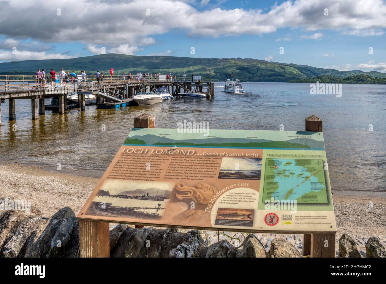 Un cartello di informazioni turistiche sulle rive del Loch Lomond al molo di Luss. Foto Stock