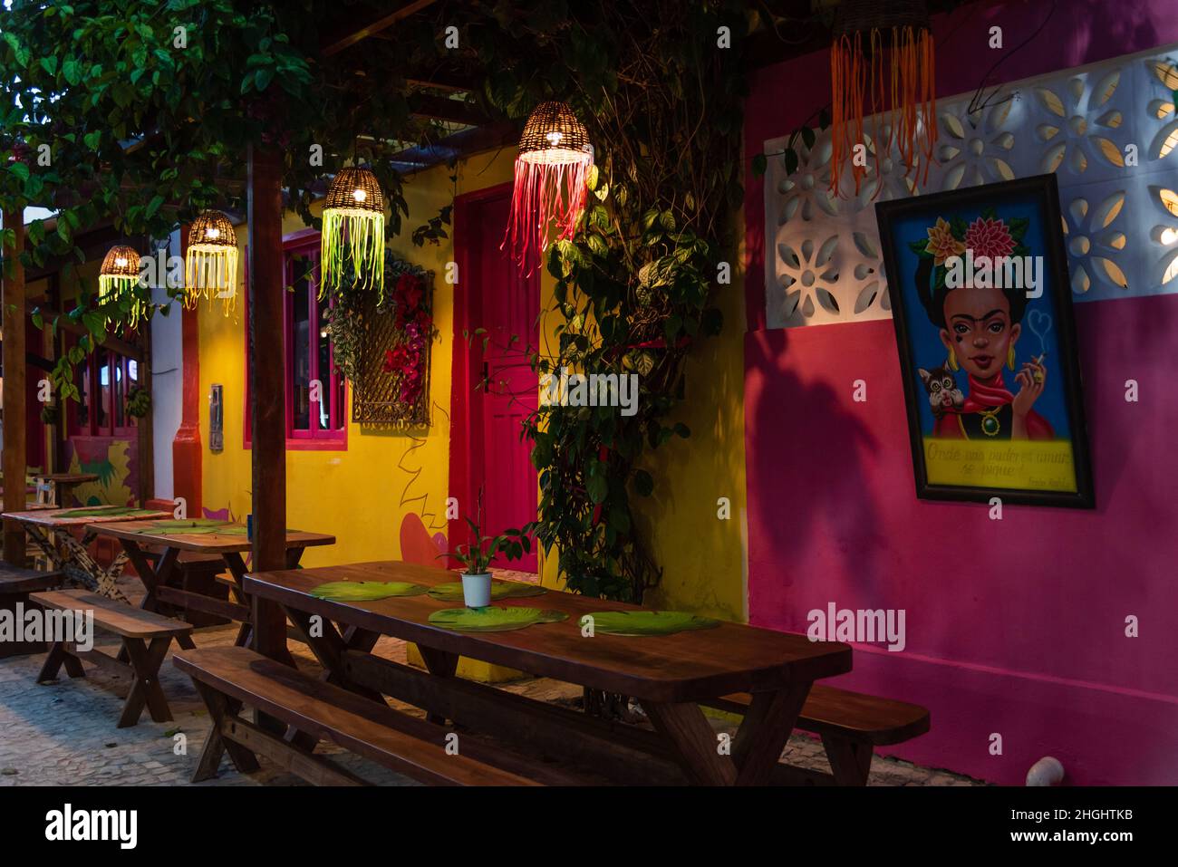 L'esterno del ristorante è colorato di giallo senape, pareti rosa e finestre e porte rosa, e lampade colorate a Beco das Garrafas, Prado, Bahia, Brasile. Foto Stock