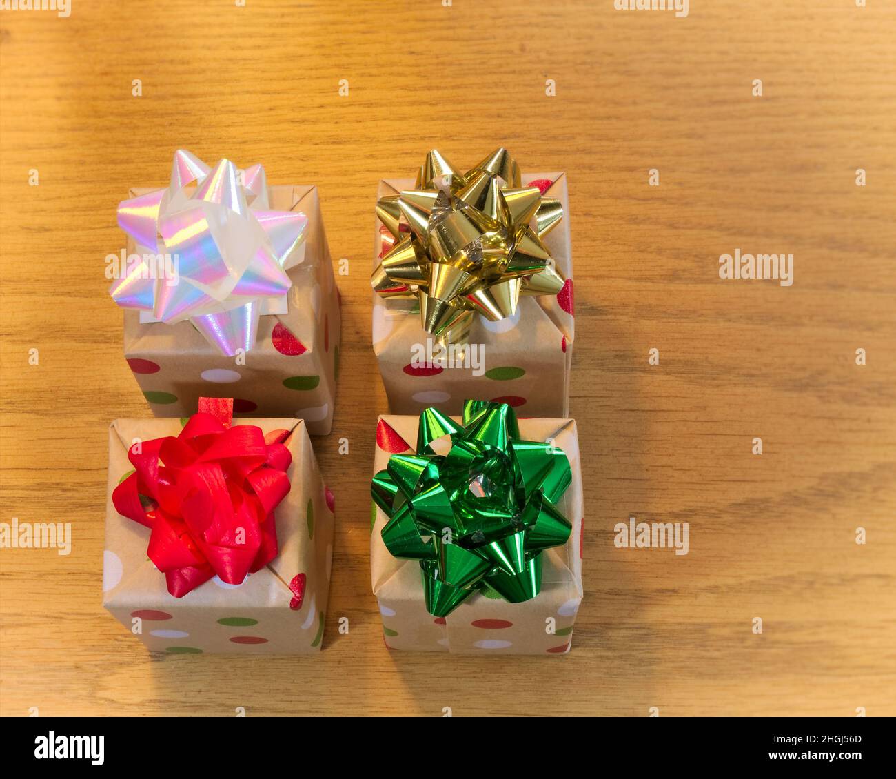 Quattro scatole regalo splendidamente avvolte su tavola di legno con archi colorati, visto dall'alto. Foto Stock