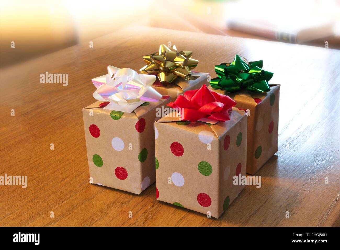 Quattro scatole regalo splendidamente avvolte su tavola di legno con archi colorati. Foto Stock